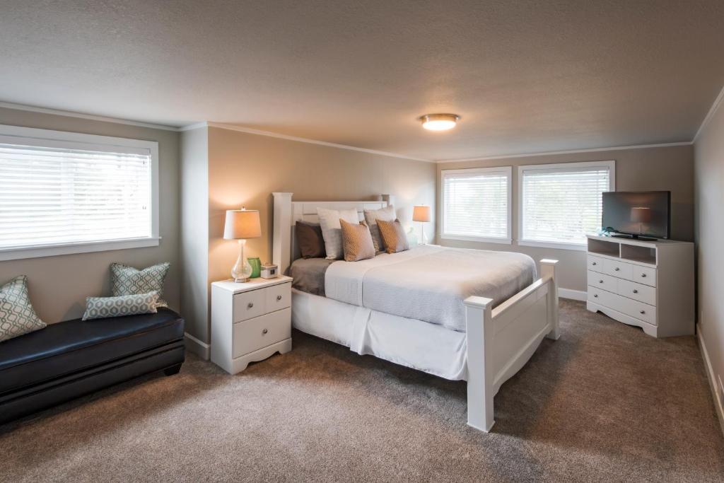 a bedroom with a bed and a tv and windows at Beach Drive Suites in Seaside