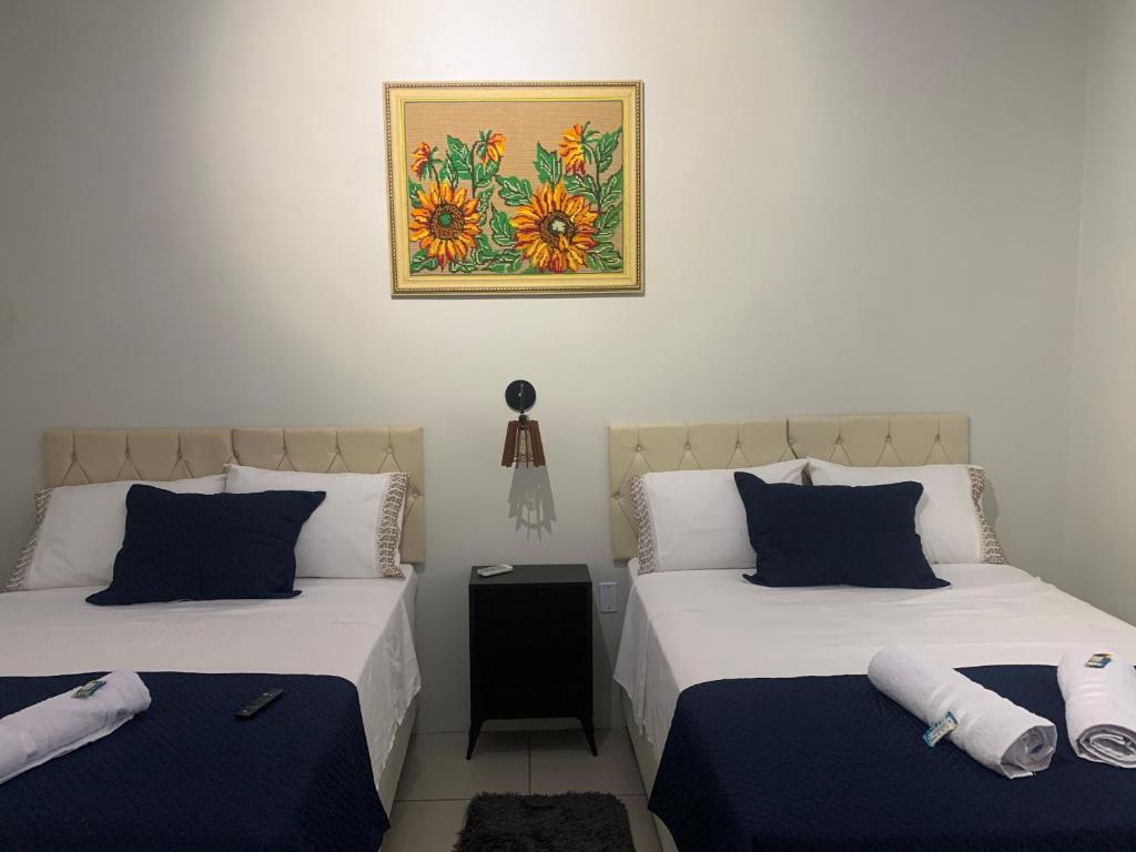 ein Schlafzimmer mit zwei Betten und einem Bild an der Wand in der Unterkunft 103-Quarto Pousada HG in Vila Nova do Sul