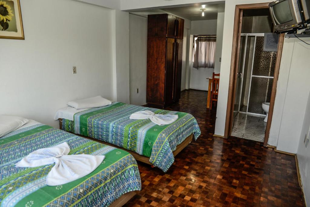 a room with two beds and a television in it at Hotel Piacenza in Caxias do Sul