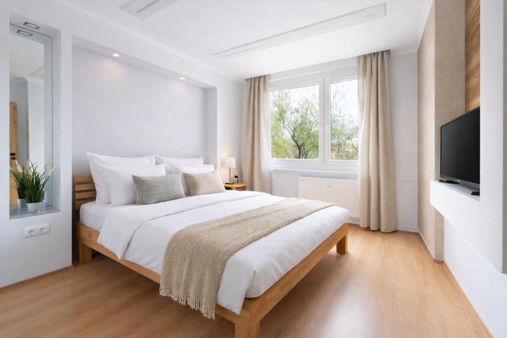 een witte slaapkamer met een groot bed en een tv bij Comfort 66 Large Family City Home in Miskolc