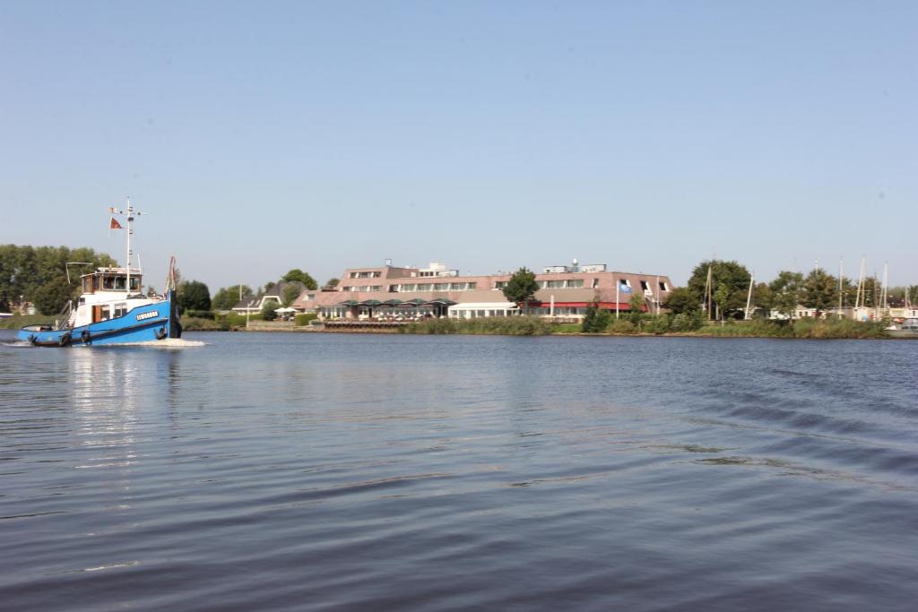 un barco azul y blanco flotando en el agua en Hotel Zwartewater en Zwartsluis