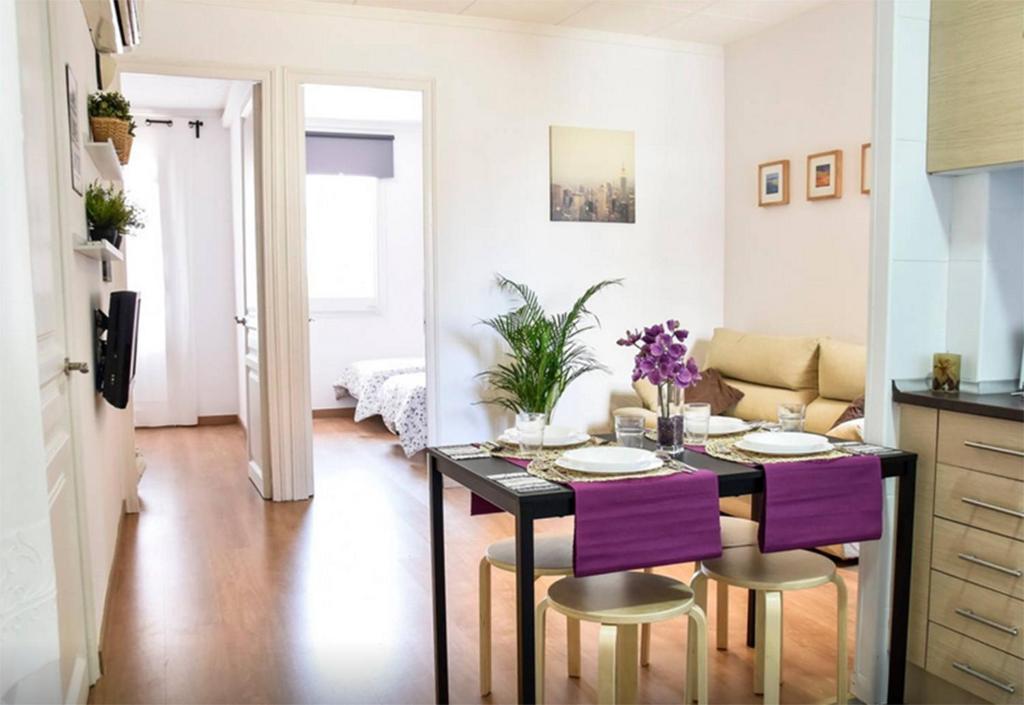 a kitchen and living room with a table and purple chairs at bcn4days 24/7 Apartments in Hospitalet de Llobregat