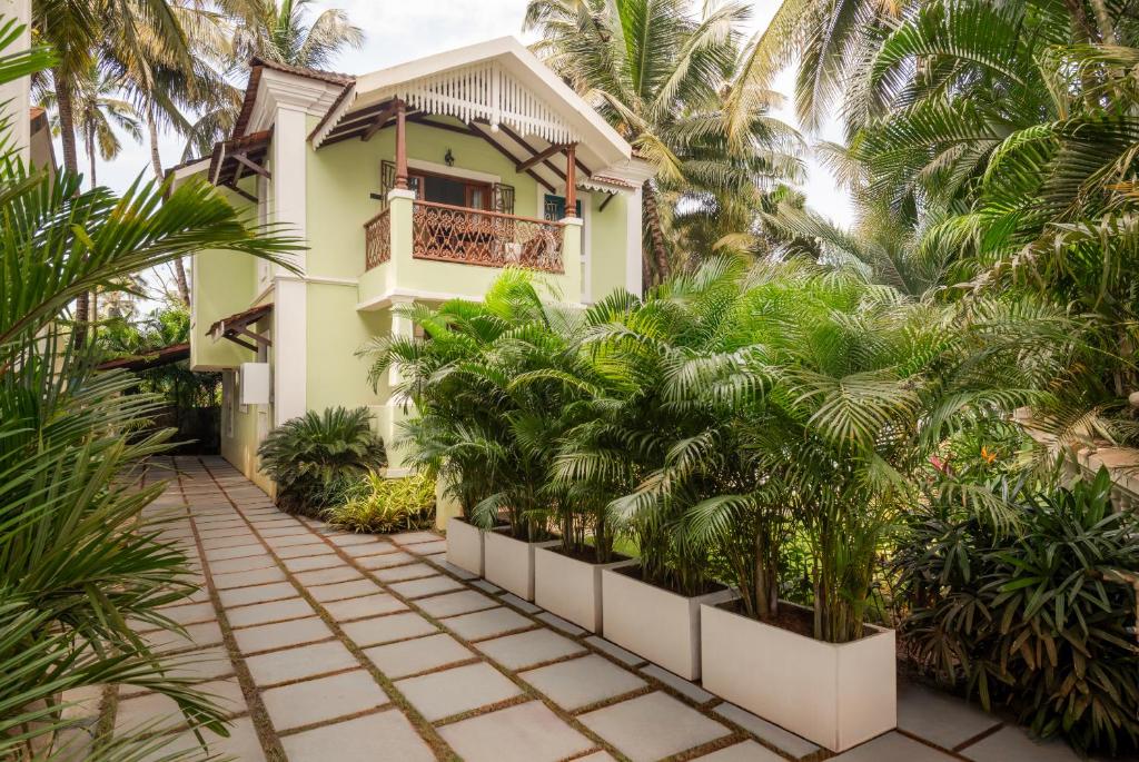 een huis met palmbomen ervoor bij Sanctuary by RÊVE Escapes - Premium 3 BHK Villa with Private Pool Near Morjim Beach in Siolim
