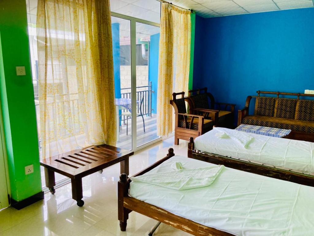 two beds in a room with a blue wall at New Verona Hotel in Wennappuwa