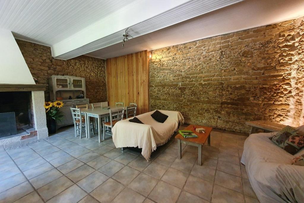 un soggiorno con tavolo e muro di mattoni di Domaine De Marlas - Gîte de Charme a Rieucros