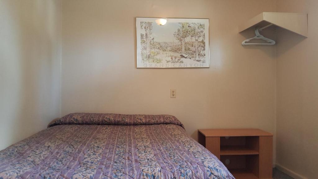 a bedroom with a bed and a picture on the wall at Hat Motel in Medicine Hat