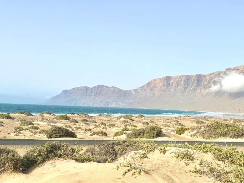 a desert with the ocean and mountains in the background at Famara Chill House in Famara