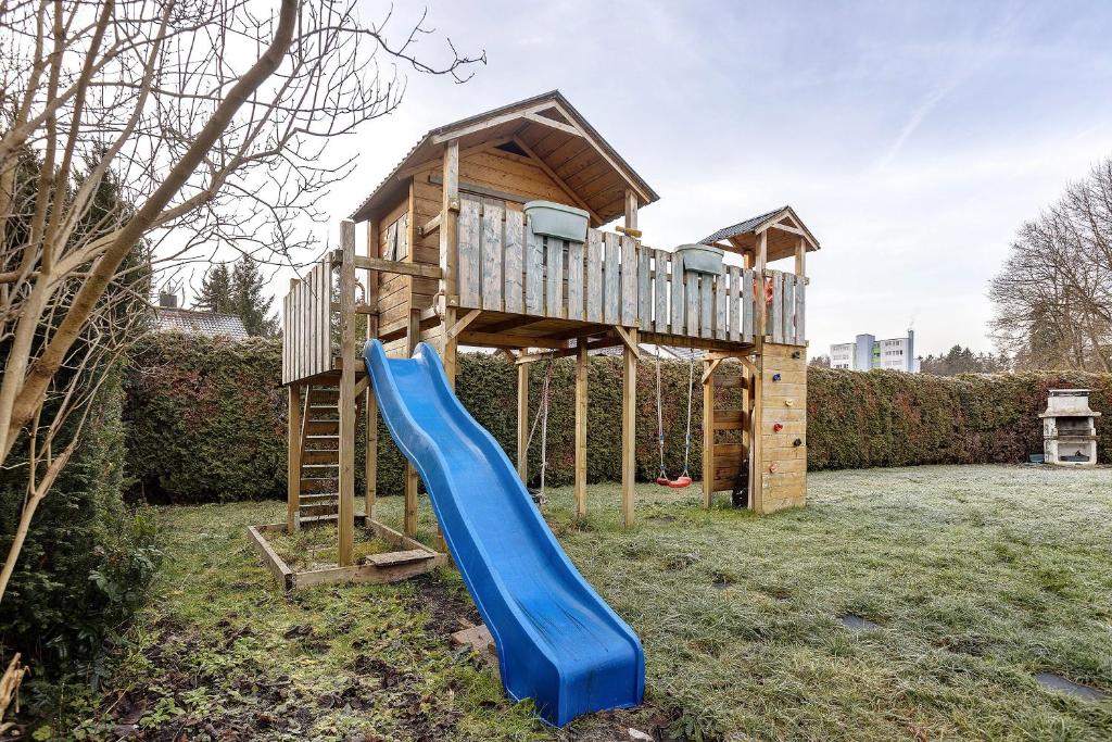 een houten speelhuis met een blauwe glijbaan bij Hivent Ferienwohnungen in Bad Dürrheim