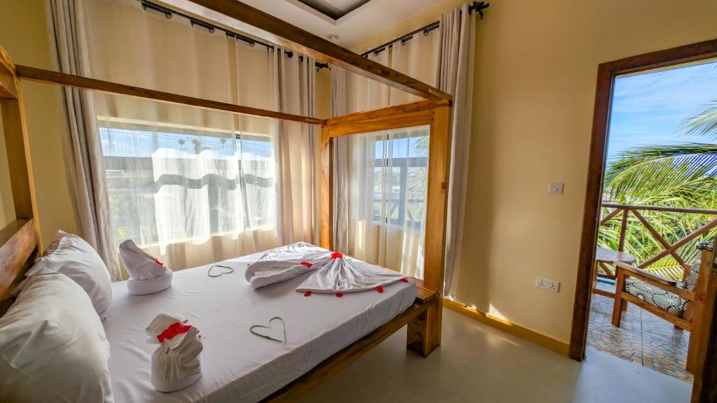 a bedroom with a bed and a large window at Joujo's Jungle Guest House in Nungwi