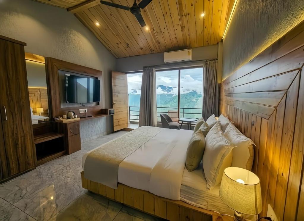 ein Schlafzimmer mit einem großen Bett mit einem großen Fenster in der Unterkunft Queen Hills Resort and Hotel By Edge Group - Rooftop Restro, Balcony View in Masuri