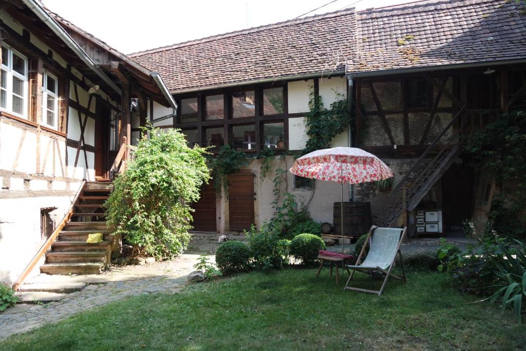 a house with a chair and an umbrella in the yard at Le temps des cigognes in Barr