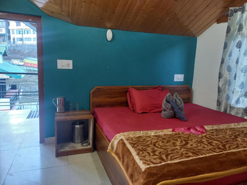 a bedroom with a bed with red sheets and a blue wall at Happy Mountains in Nārkanda