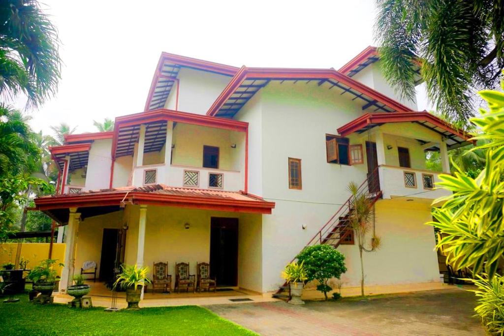 a white and yellow house with a yard at Bentota Backpackers Bay Hostel in Bentota