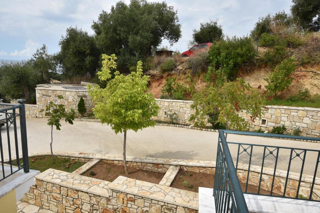 a garden with a retaining wall and a tree at Sivota Apartments in Syvota