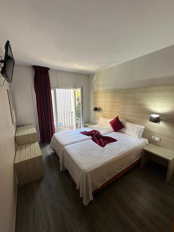 Hotel Norai في يوريت دي مار: غرفة نوم بسرير كبير عليها قوس احمر