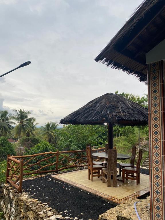 a patio with a table and chairs and an umbrella at Batukaras beach hill villas in Batukaras