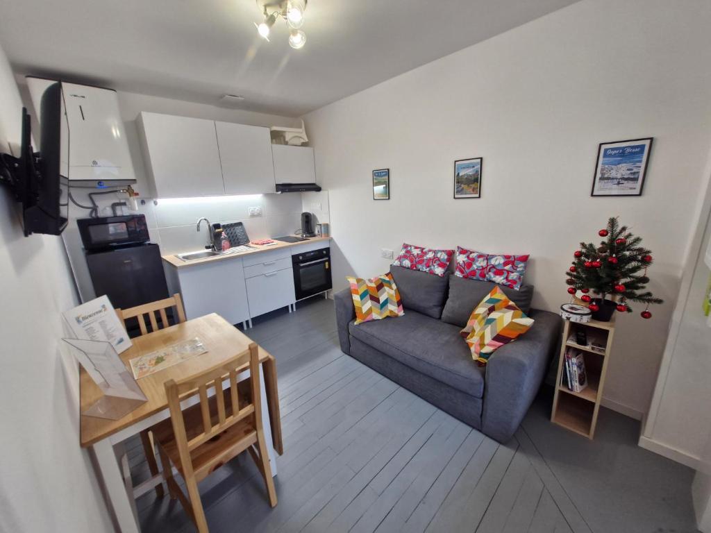 ein Wohnzimmer mit einem Sofa und eine Küche mit einem Weihnachtsbaum in der Unterkunft Appartement F2 5B in Martres-de-Veyre