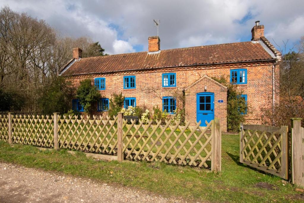 an old brick house with blue windows and a fence at 5 Bed in Hindolveston oc-d29357 in Hindolveston