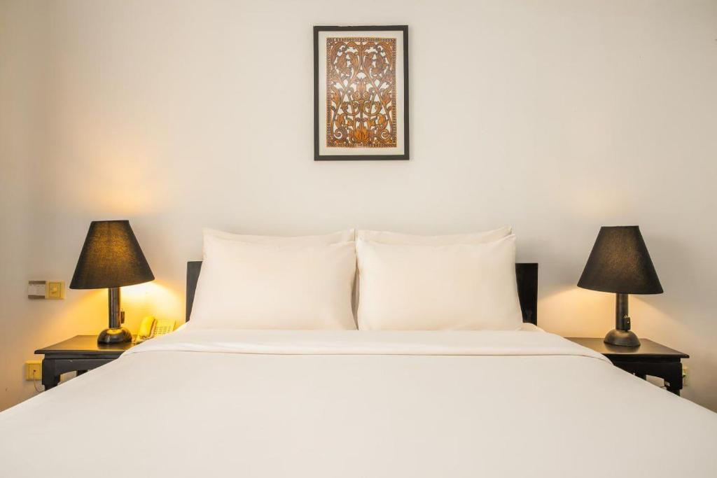 een slaapkamer met een groot wit bed met twee lampen bij Apsara Centrepole Hotel in Siem Reap