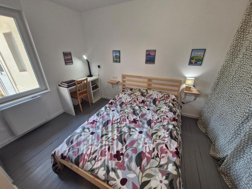 een slaapkamer met een bed, een bureau en een raam bij Appartement F2 5A in Martres-de-Veyre