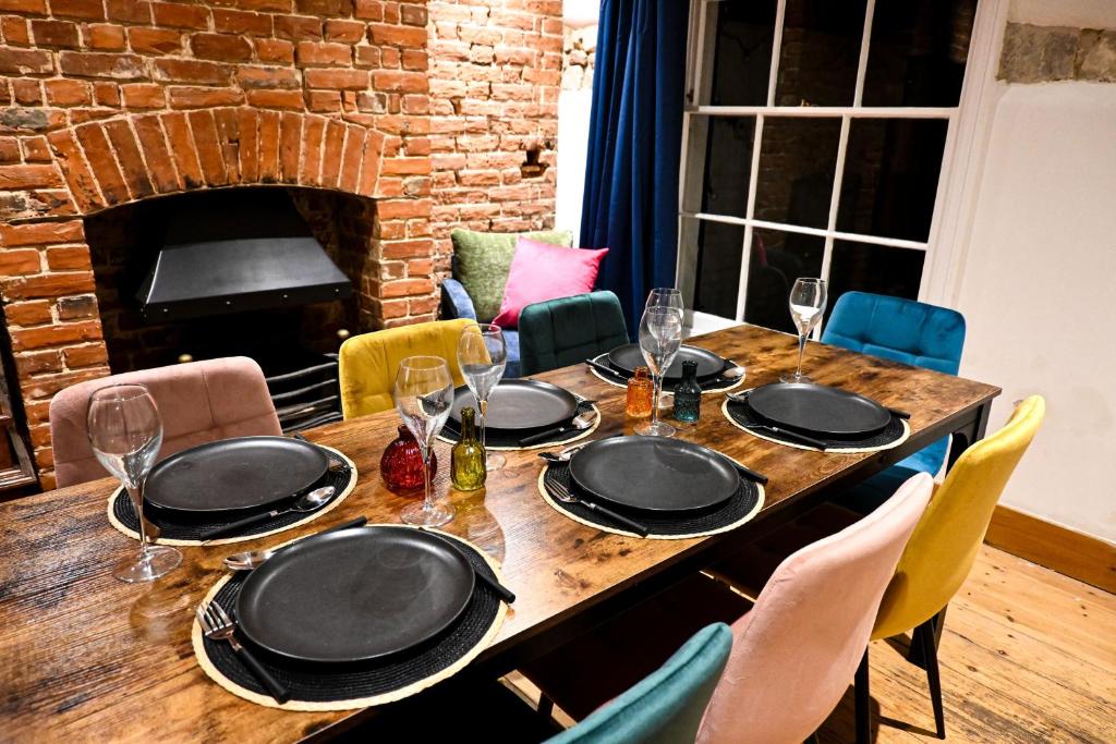 a table with plates and glasses on it with a fireplace at Cathedral Cottage in Canterbury