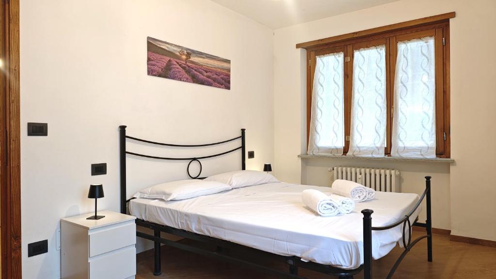 ein Schlafzimmer mit einem Bett mit weißer Bettwäsche und einem Fenster in der Unterkunft Hostdomus - Chez Paul in Cesana Torinese
