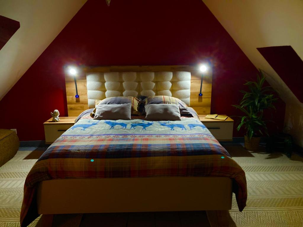 a bedroom with a large bed in a red wall at Le petit secret au pied du zoo in Saint-Aignan