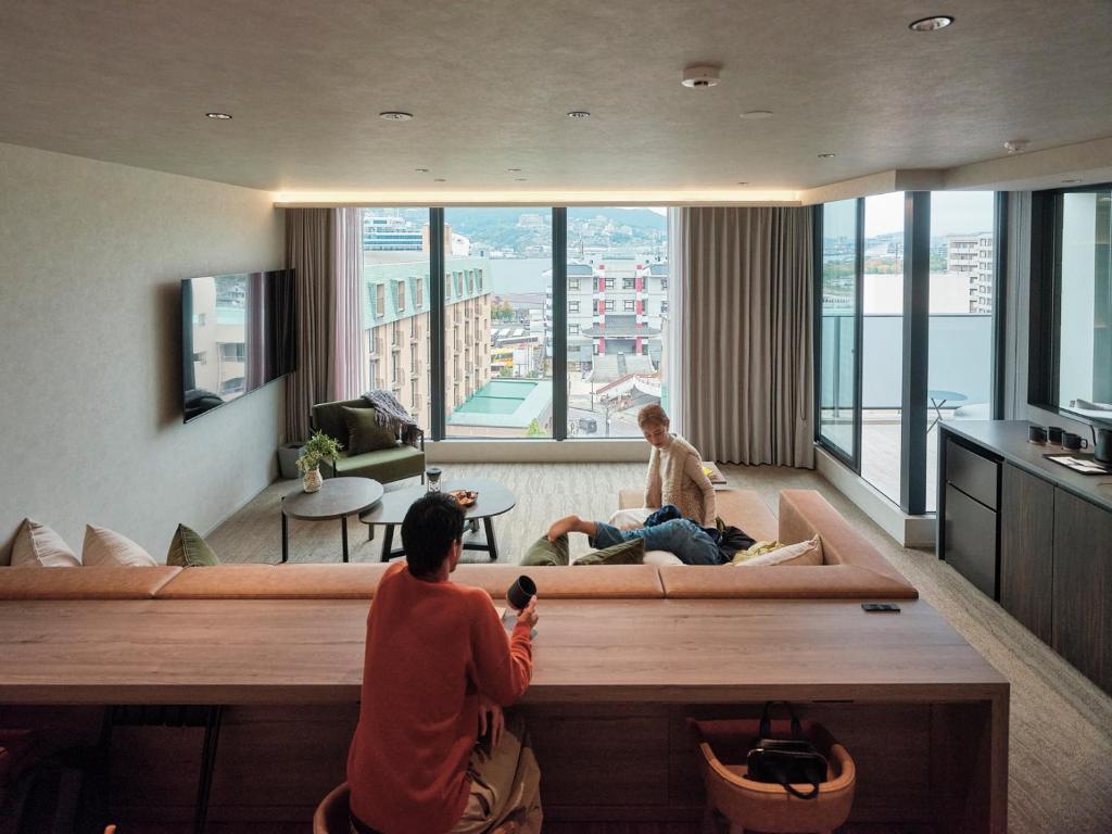 two people sitting on a couch in a living room at FAV LUX Nagasaki in Nagasaki