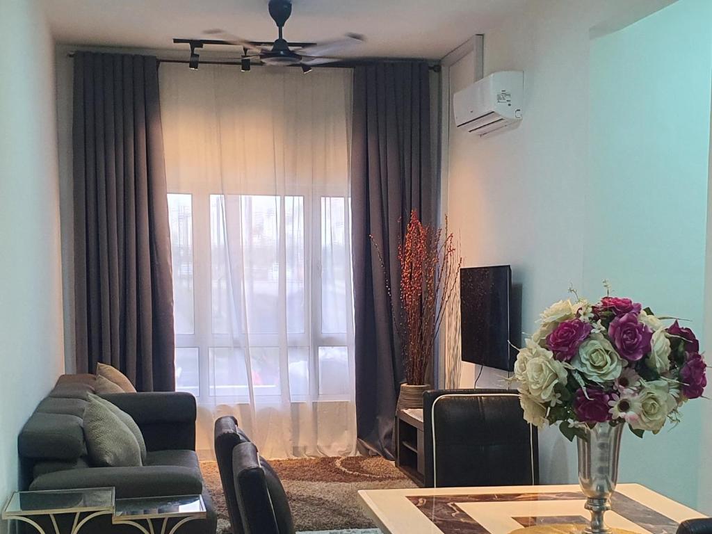 ein Wohnzimmer mit einer Couch und einem Tisch mit Blumen in der Unterkunft My HomeStay 02 Aspire Residence Family Friendly Unit - Ground Floor in Cyberjaya