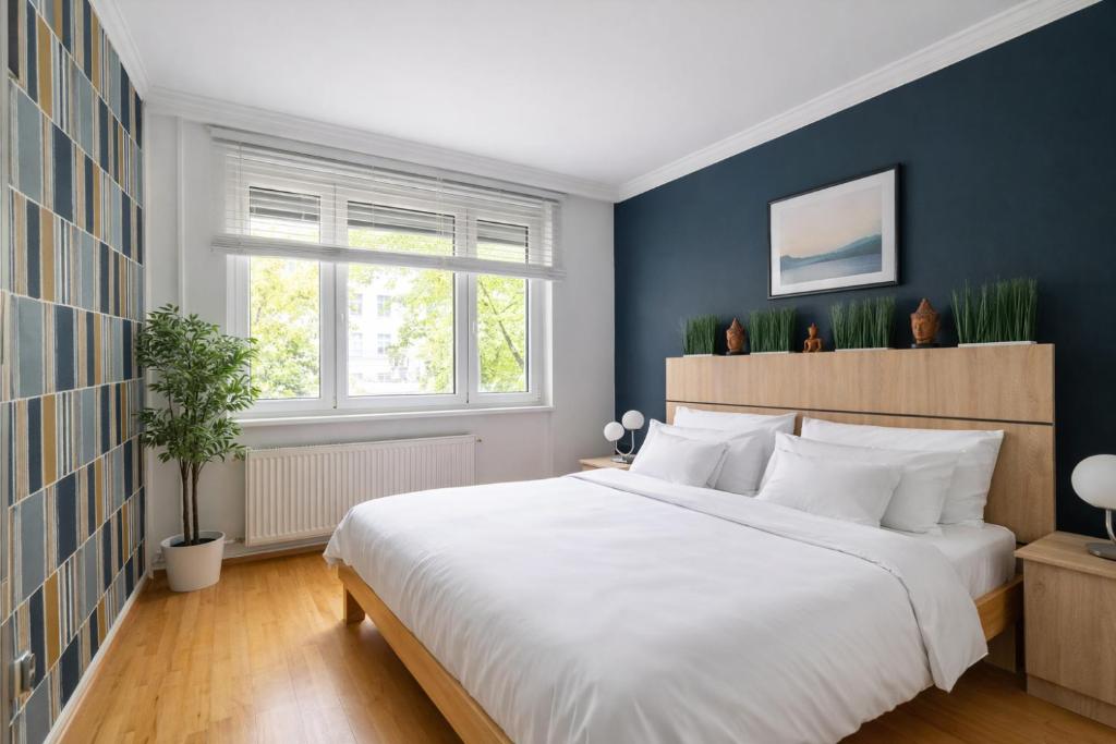 een slaapkamer met een wit bed en een blauwe muur bij Comfort 28 Parkside Comfort in Miskolc