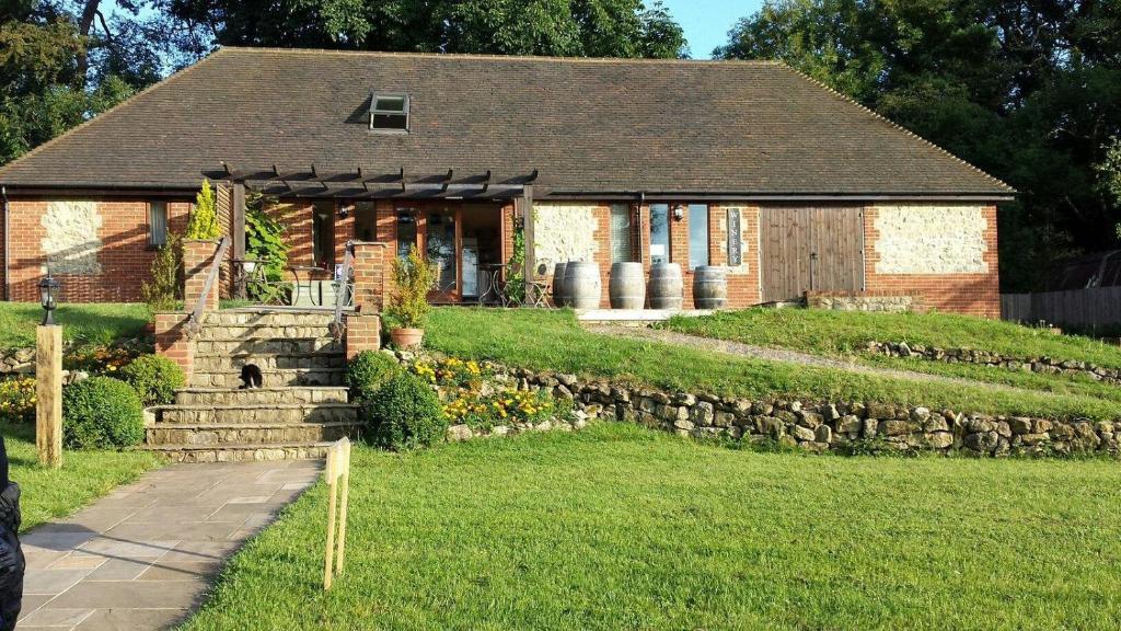 ein Backsteinhaus mit einer Steinmauer neben einem Hof in der Unterkunft Terlingham Lane Cottage in Folkestone