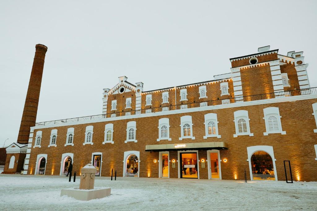 a large brick building with a clock tower on top at Pana Unique Semey in Semey
