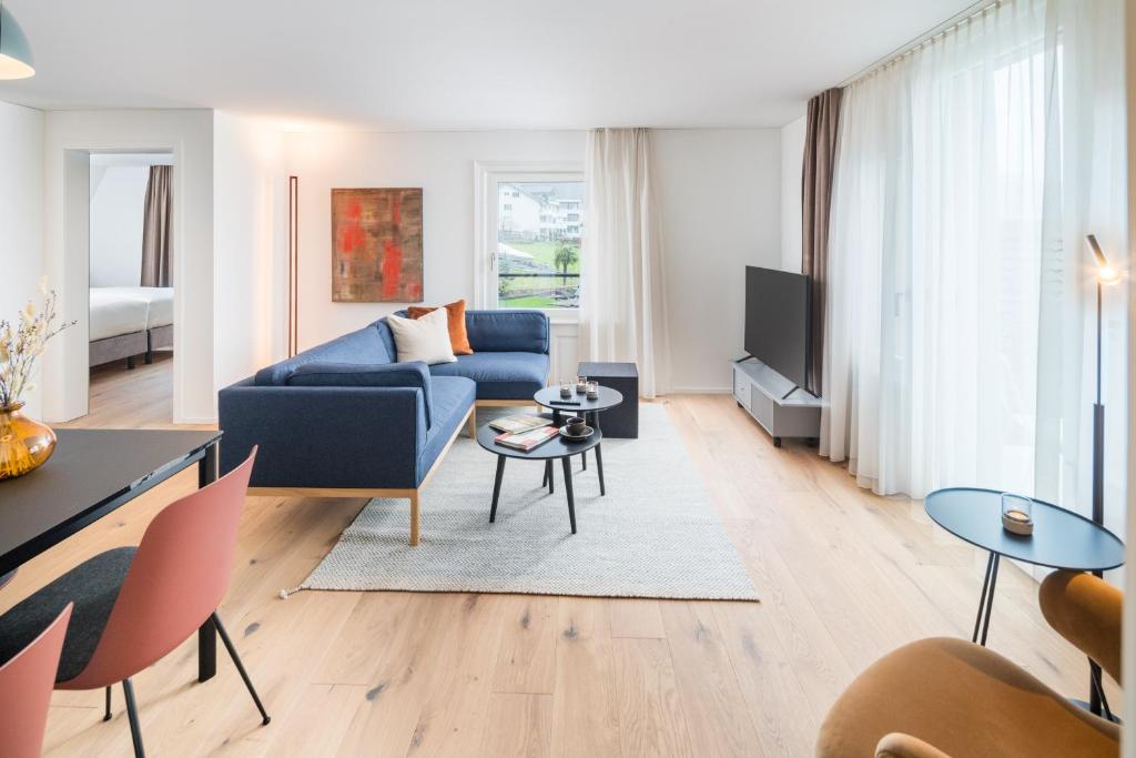 a living room with a blue couch and a tv at Apartments Quellenhöfli in Vitznau