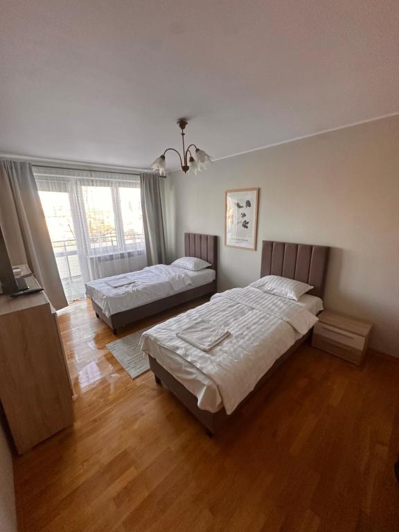 een slaapkamer met twee bedden en een groot raam bij Przytulnie i wszędzie blisko in Siedlce