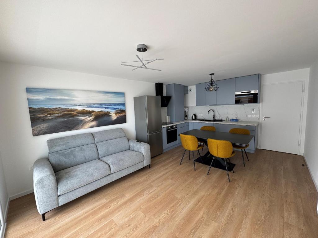 ein Wohnzimmer und eine Küche mit Sofa und Tisch in der Unterkunft Escapade à Sainte-Cécile 2 chambres, balcon, plage à 50m in Camiers