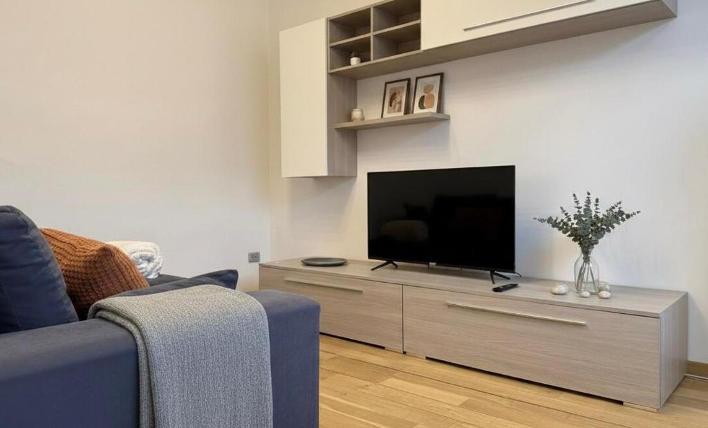 a living room with a flat screen tv on a entertainment center at Fiume 34 - bilocale luminoso e moderno a Sondrio in Sondrio