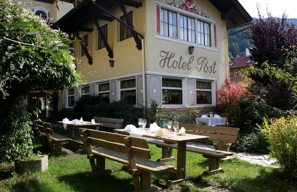 una mesa y bancos frente a un edificio en Hotel Post en Großkirchheim