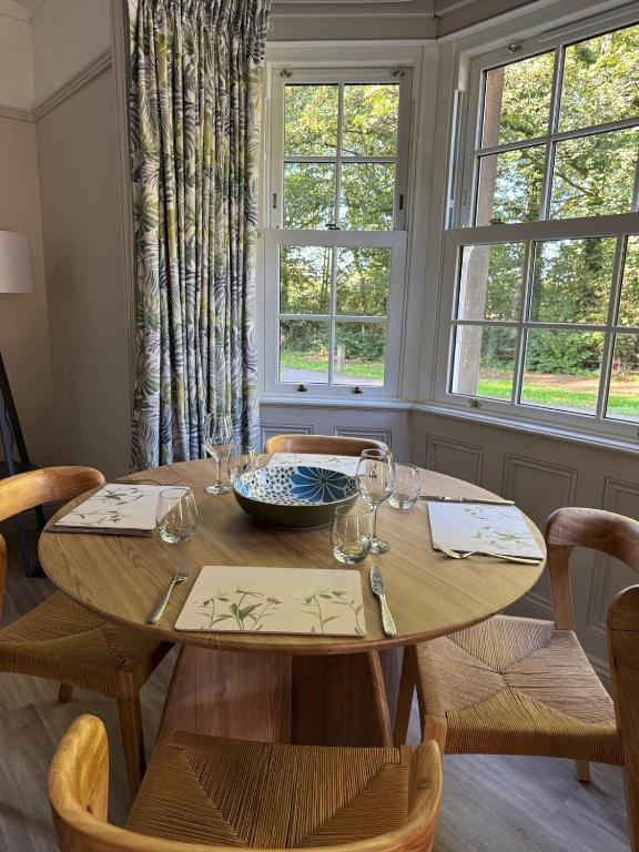 a dining room table with chairs and a table and two windows at Spofforth Lodge in Wetherby