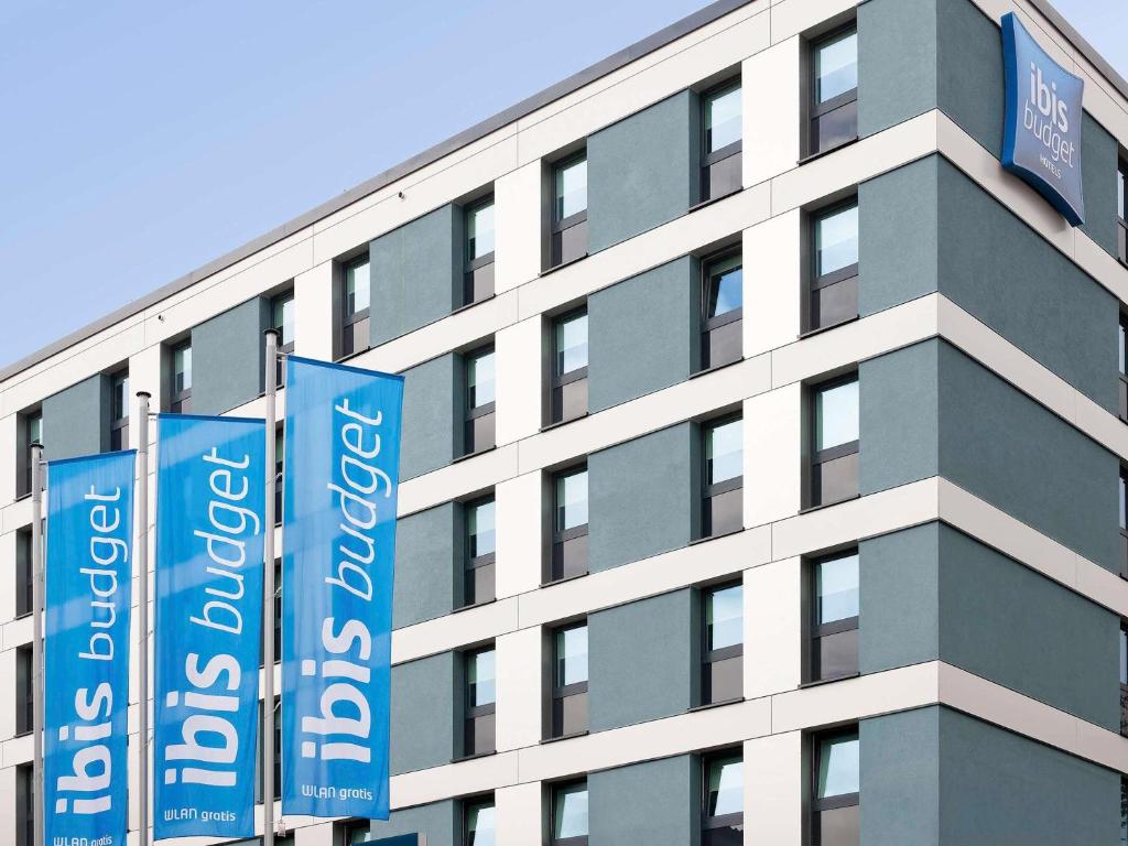 een hoog gebouw met blauwe banners ervoor bij Ibis budget Koeln Messe in Keulen