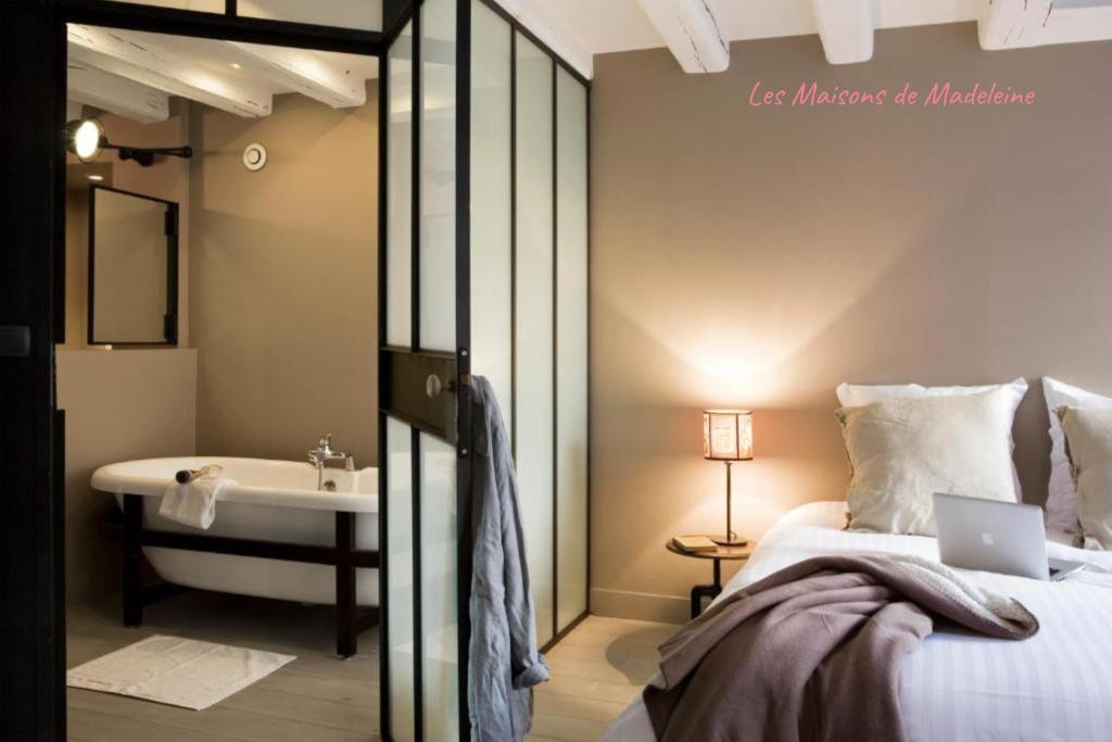 een slaapkamer met een bed en een badkamer met een wastafel bij La Nuit - Suite avec baignoire in Nantes