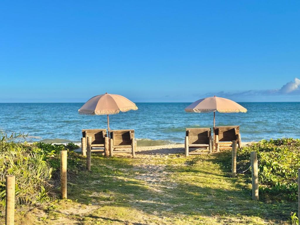 two tables and umbrellas on a beach near the water at Kokar Casa Hotel SANTO ANDRÉ in Santo André