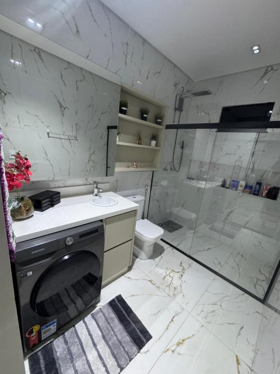 a bathroom with a washing machine and a shower at Casa completa acomoda até 10 hóspedes, 5 quartos, 4 camas casal e 2 solteiro in Ponta Porã