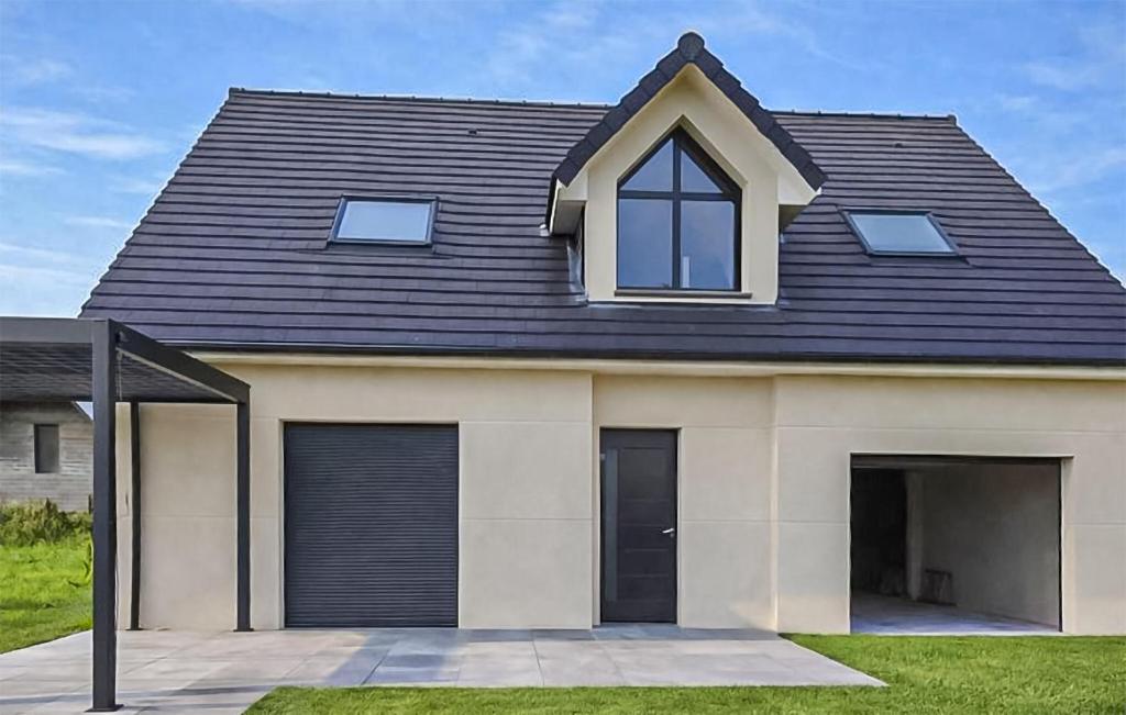 une maison avec un toit mansardé et un garage dans l'établissement Maison Campagne Normandie, à Ry