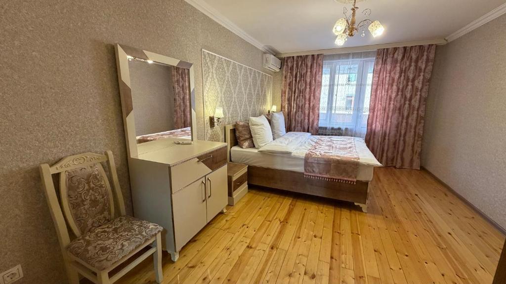 ein Schlafzimmer mit einem Bett, einem Spiegel und einem Stuhl in der Unterkunft Sheki Central Apartment Deluxe in Şəki