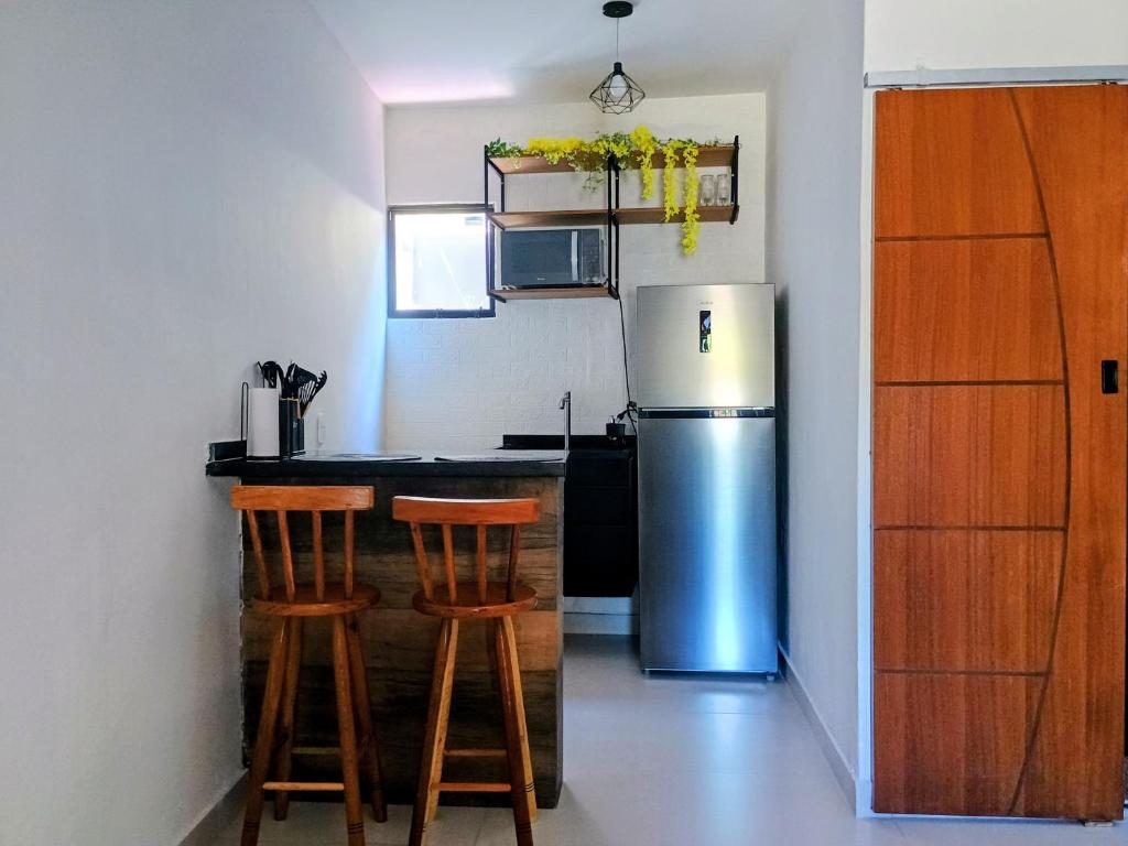 a kitchen with a stainless steel refrigerator and two bar stools at Flat confortavel e aconchegante in Cabo Frio