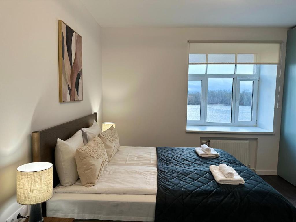 a bedroom with a bed with two towels on it at Panoramic River View I Spacious Modern 2BR Apartment in Riga