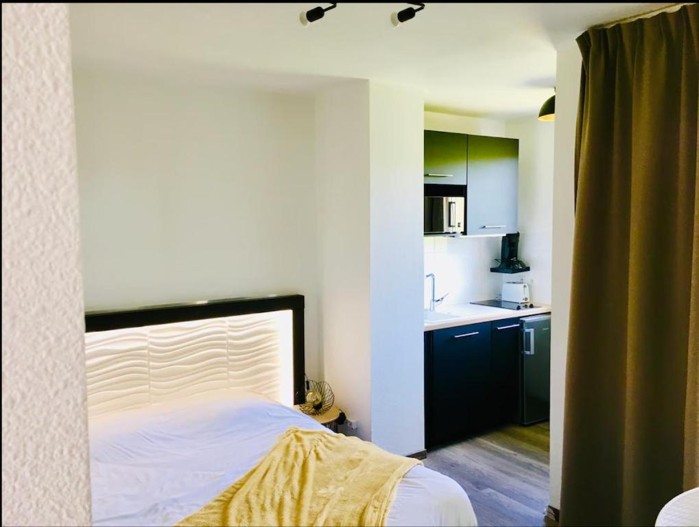 ein kleines Schlafzimmer mit einem Bett und einer Küche in der Unterkunft Studio moderne avec Balcon à 5 min de Honfleur parking et piscine in Équemauville