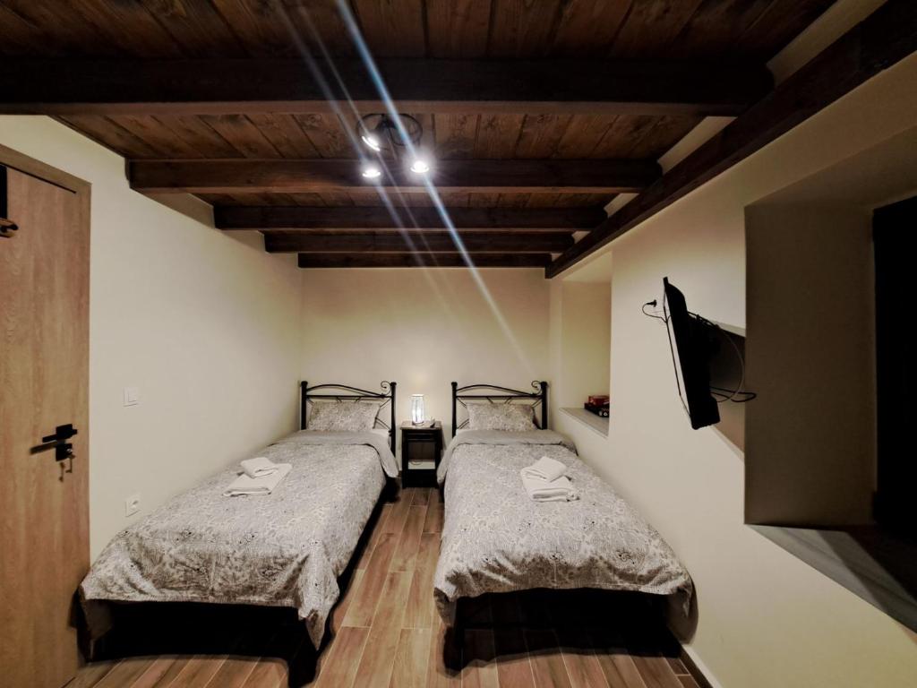 due letti in una stanza con soffitti in legno di Αυγήλιον - Private Mountain House a Synikia Mesi Trikalon