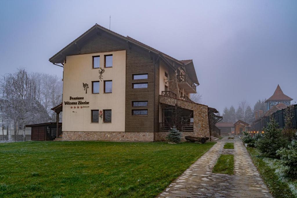een groot huis met een grasveld ervoor bij Vâlceaua Zânelor in Stațiunea Climaterică Sâmbăta