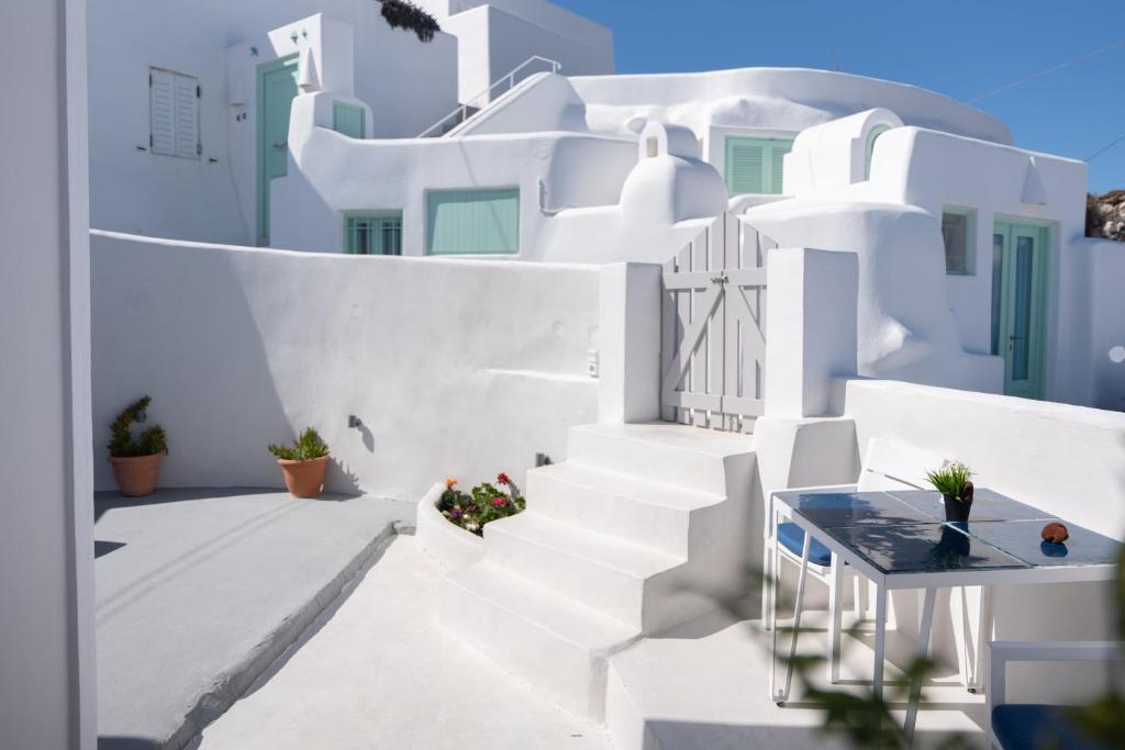 Blick auf ein weißes Haus mit Treppe und Pflanzen in der Unterkunft White Swallow Suite Santorini in Vourvoúlos